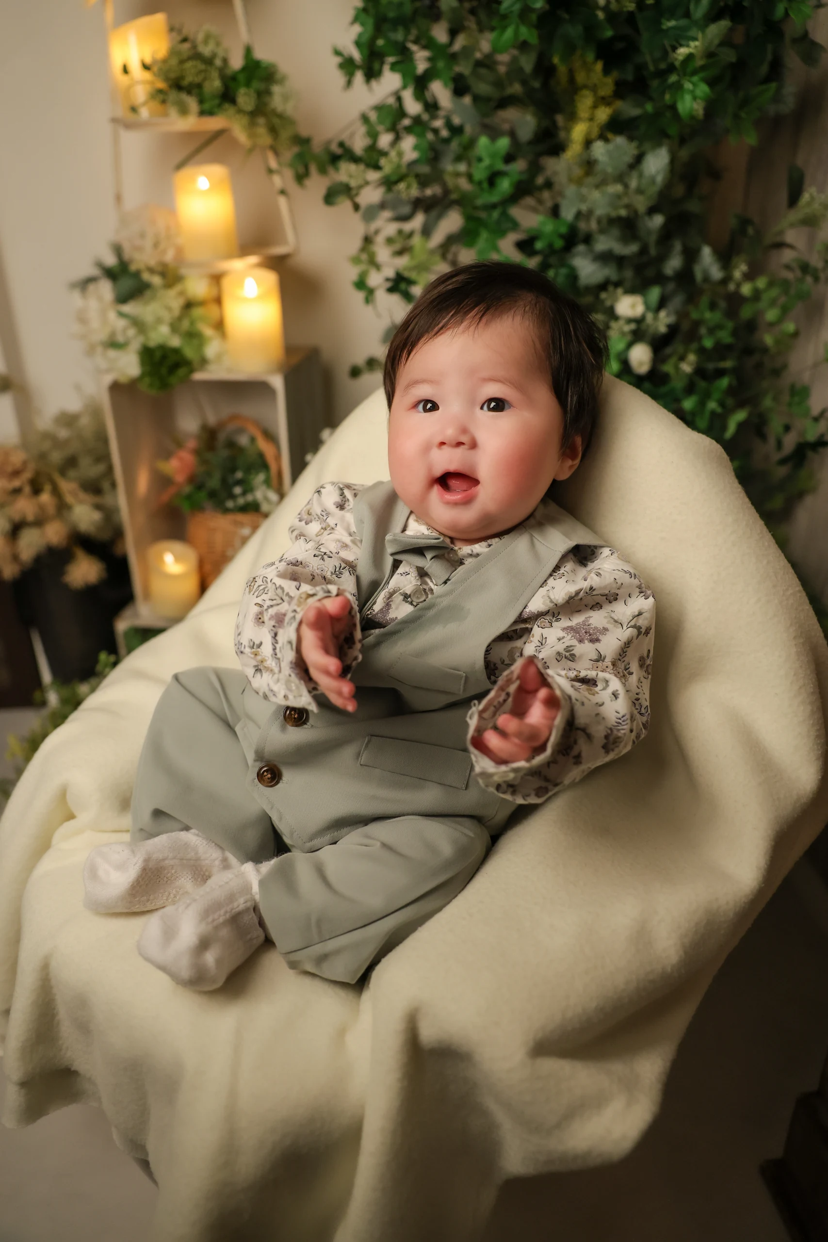ベスト姿で緑に囲まれた椅子に座る赤ちゃん