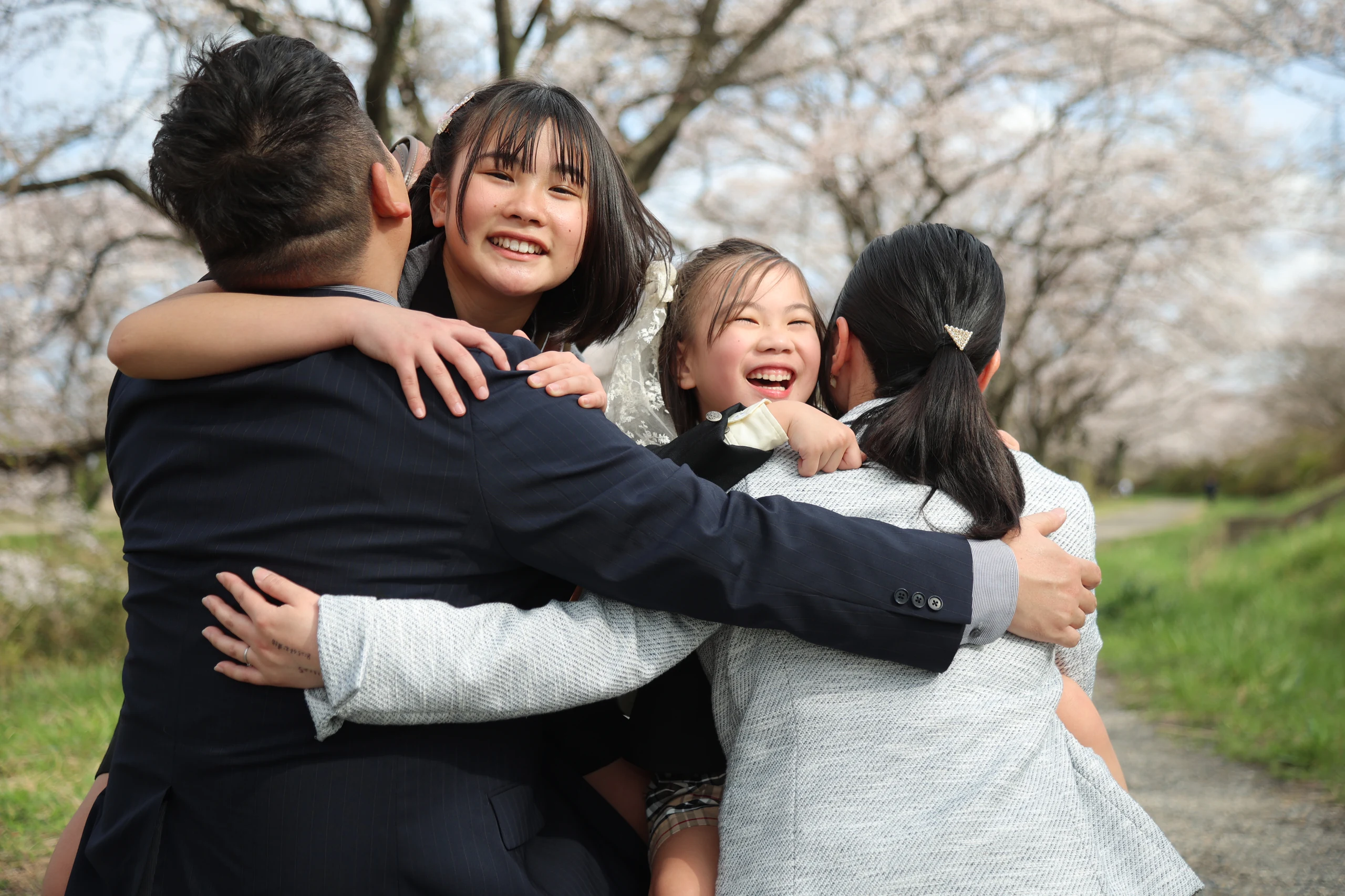 桜の下で互いに抱き合って笑う家族
