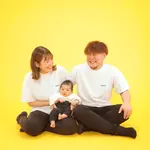 Parents sitting around a baby on a yellow background