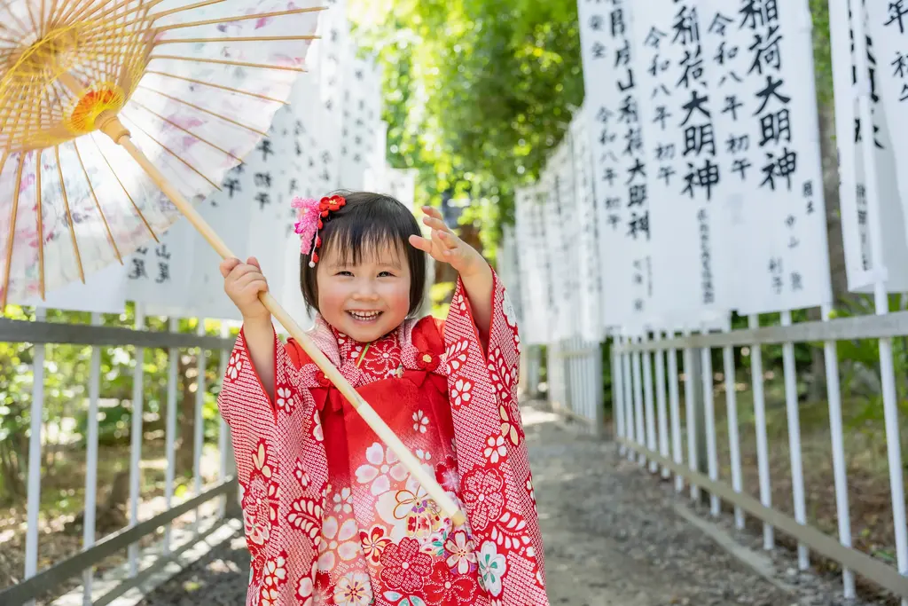神社の参道で和傘を手に笑うお子さま