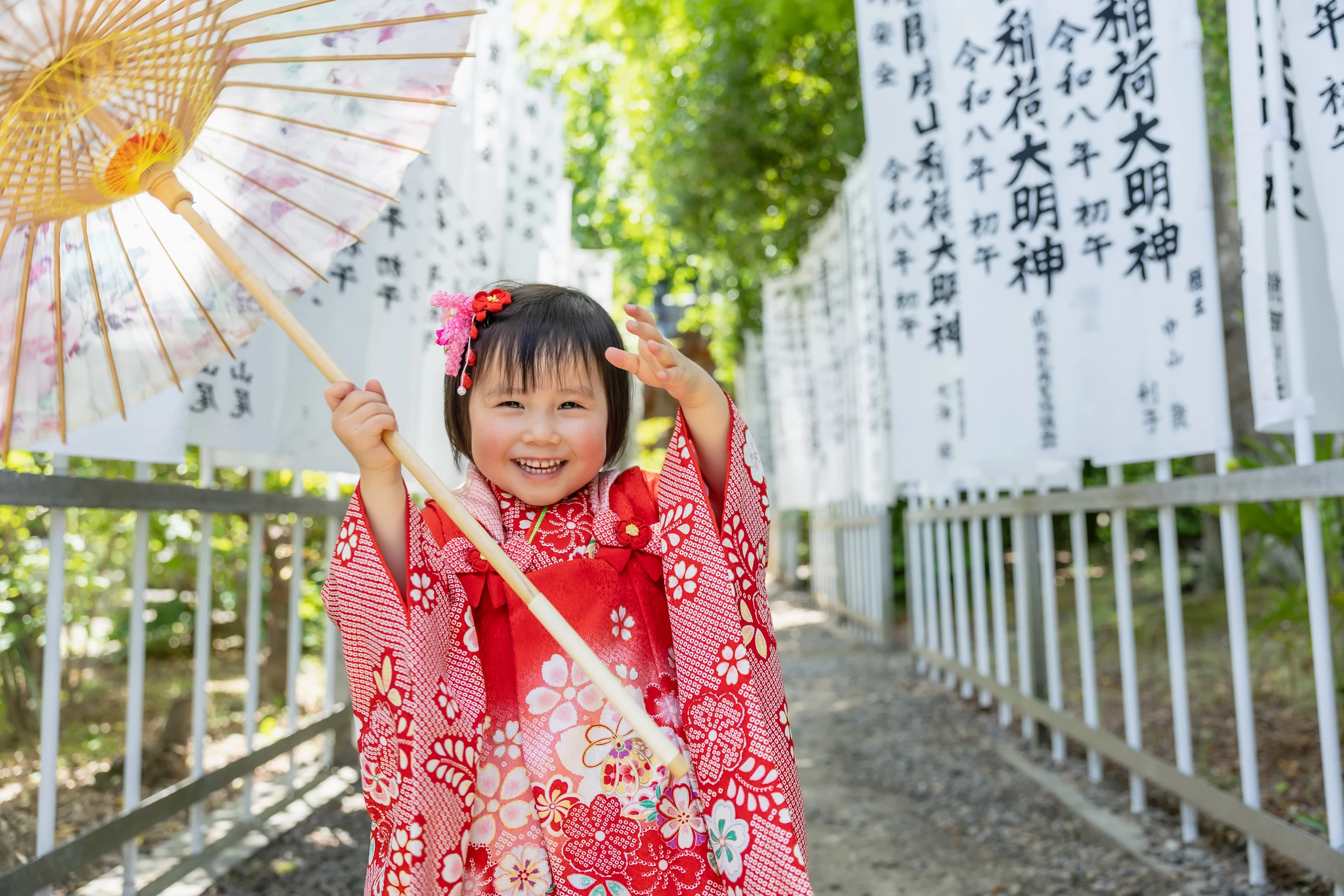 神社の参道で和傘を持って笑う七五三のロケーション写真