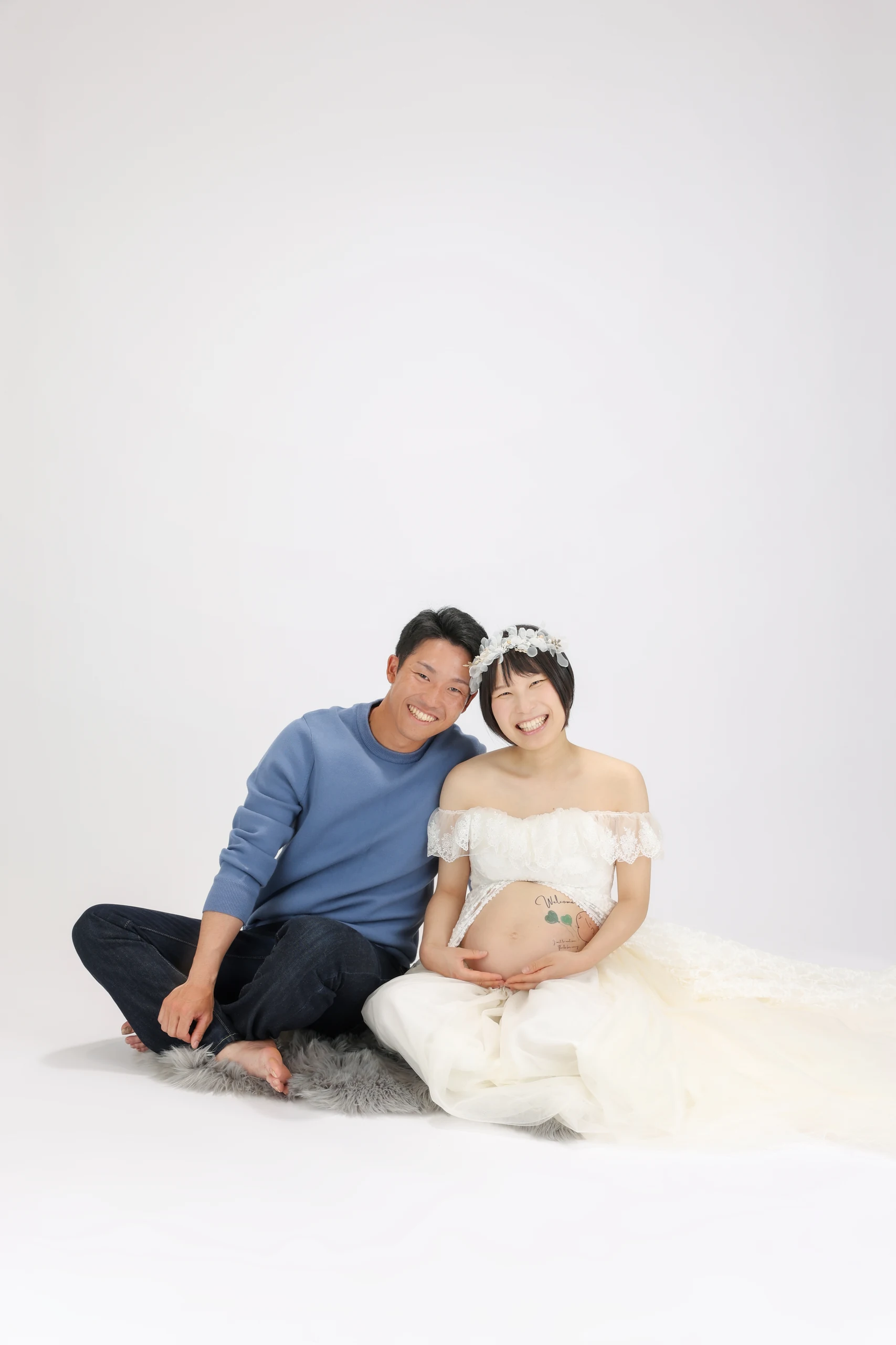 A married couple sitting close to a pregnant woman in a white dress