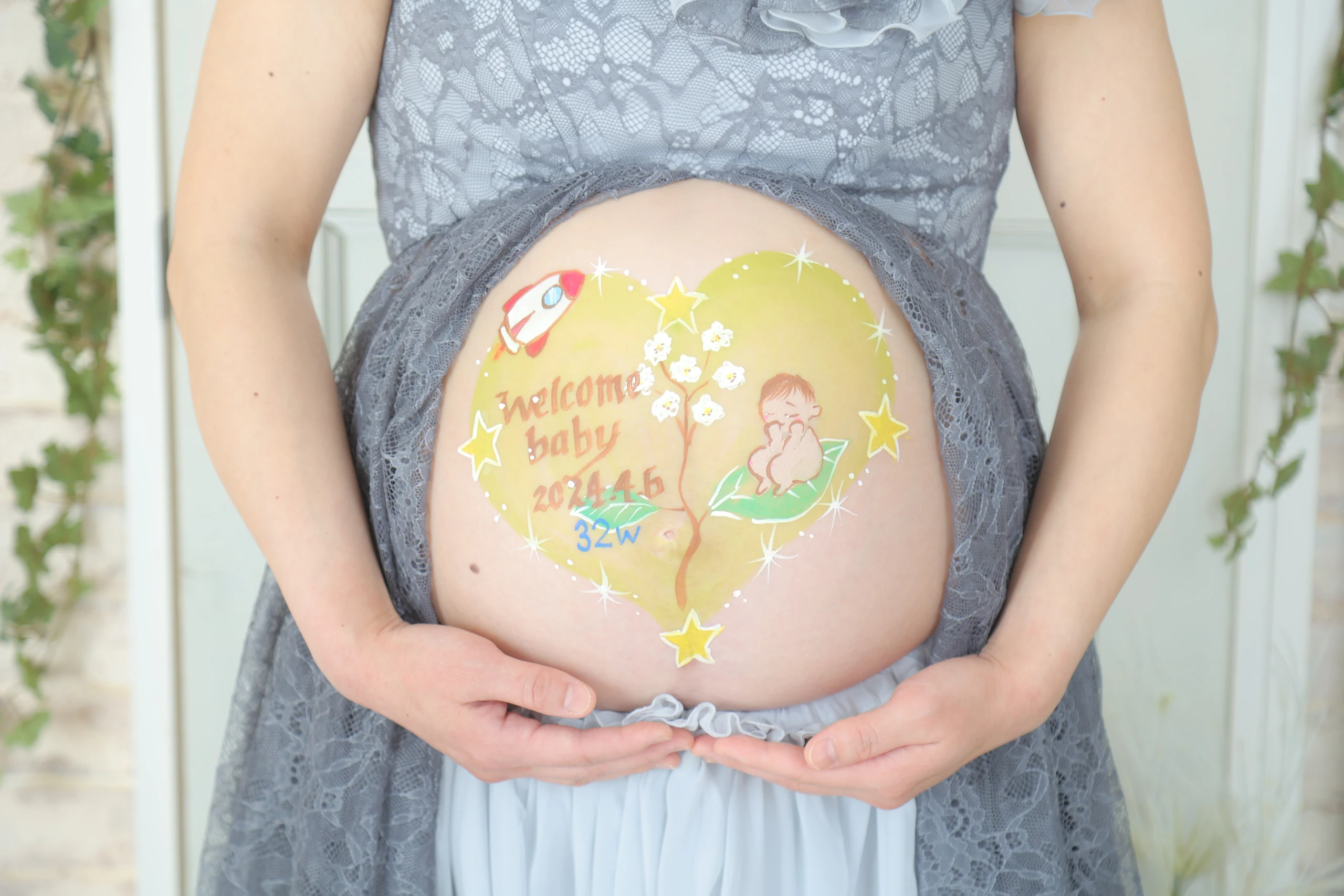 A pregnant woman cradling colorful belly paint in both hands