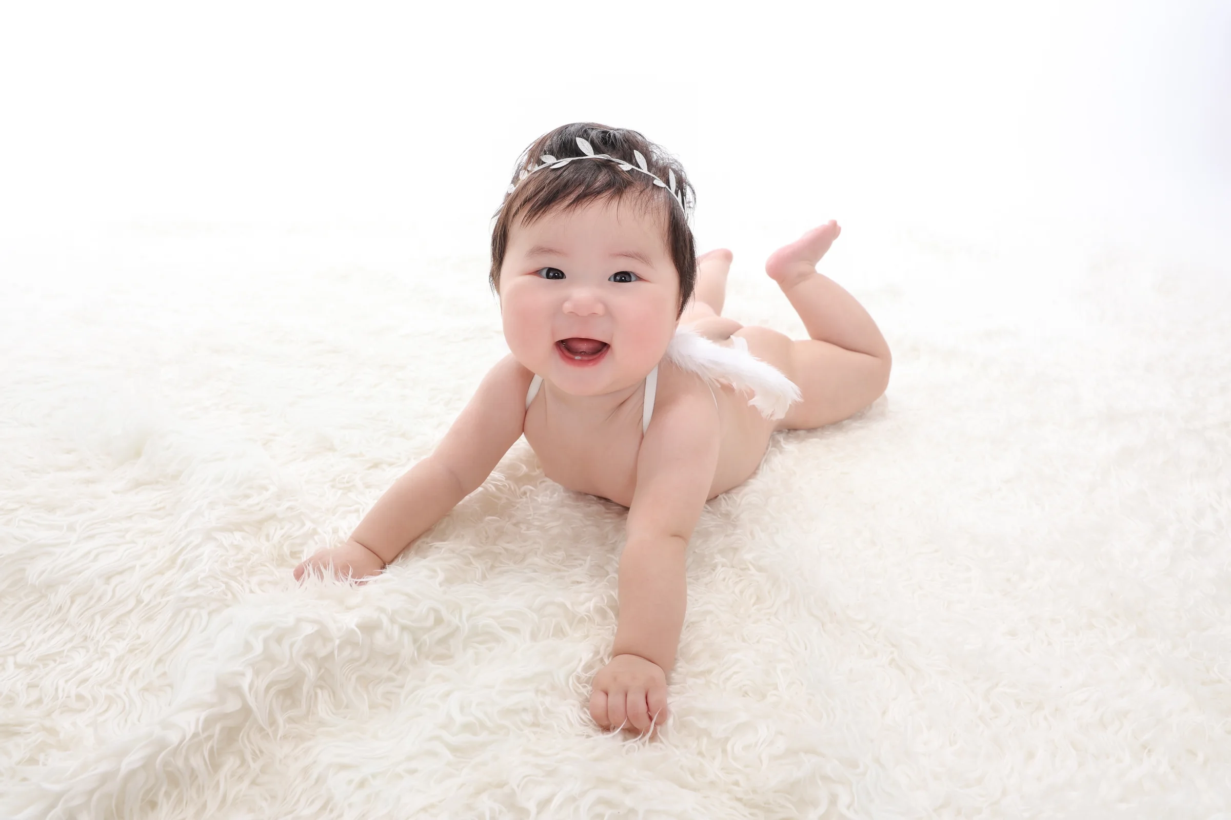 白いラグの上で笑顔を見せる赤ちゃん