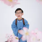 Children smiling in blue kindergarten uniforms and carrying school backpacks, surrounded by cherry blossoms