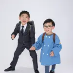 Siblings holding hands and running in a suit and a blue kindergarten uniform