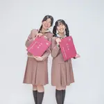 Two students in uniform lining up with their graduation certificates