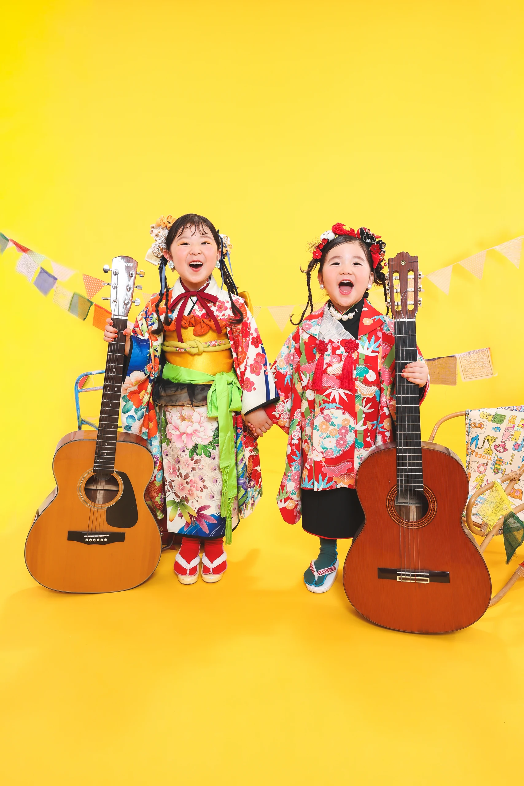 黄色い背景で和装姿のきょうだいが並んで笑う七五三写真
