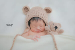 くまの帽子をかぶって眠るニューボーンフォトの赤ちゃん