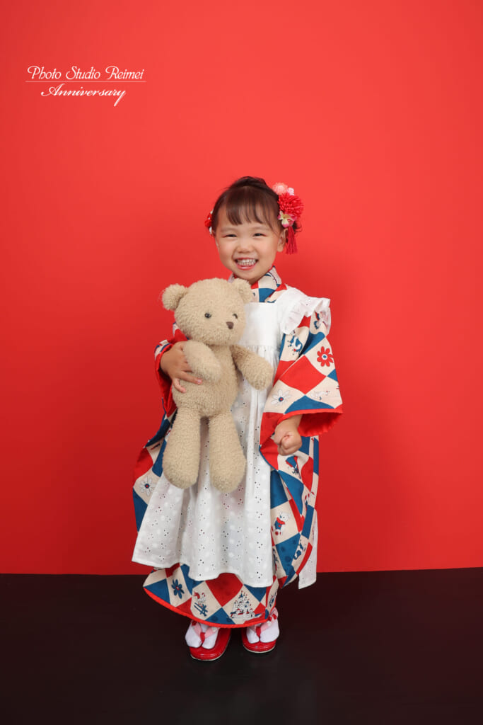 ぬいぐるみを抱いて笑う着物姿のお子さま