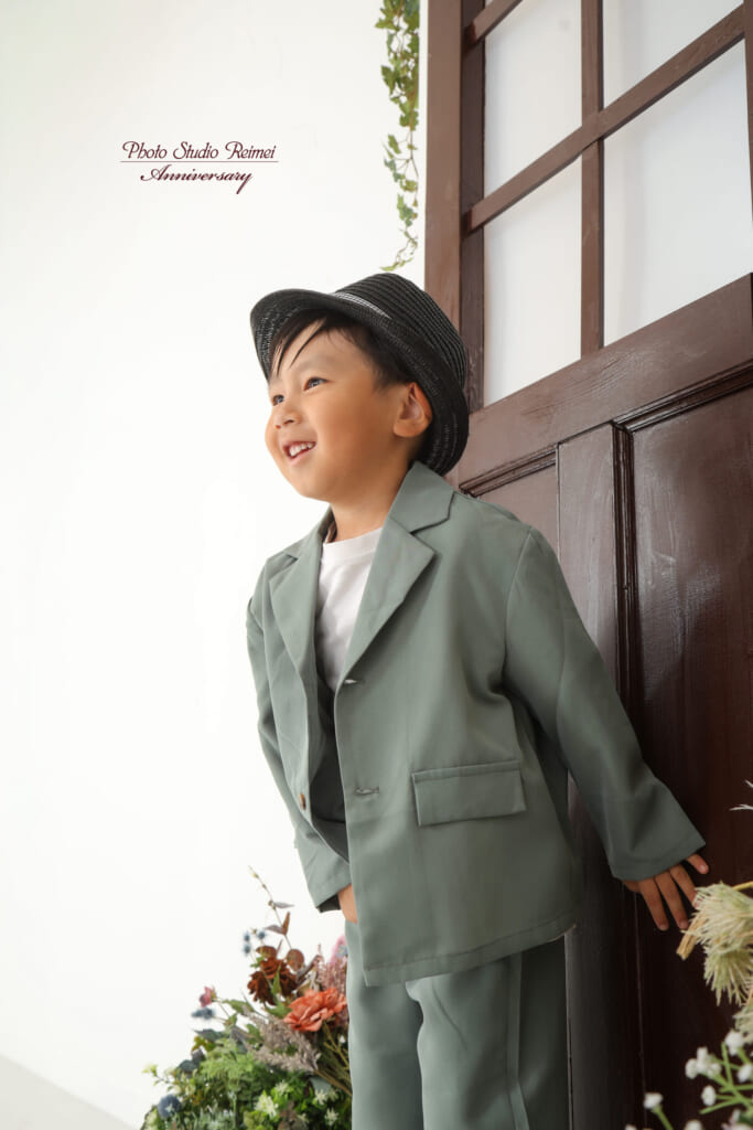 窓辺に立つ、グリーンのスーツ姿のお子さま