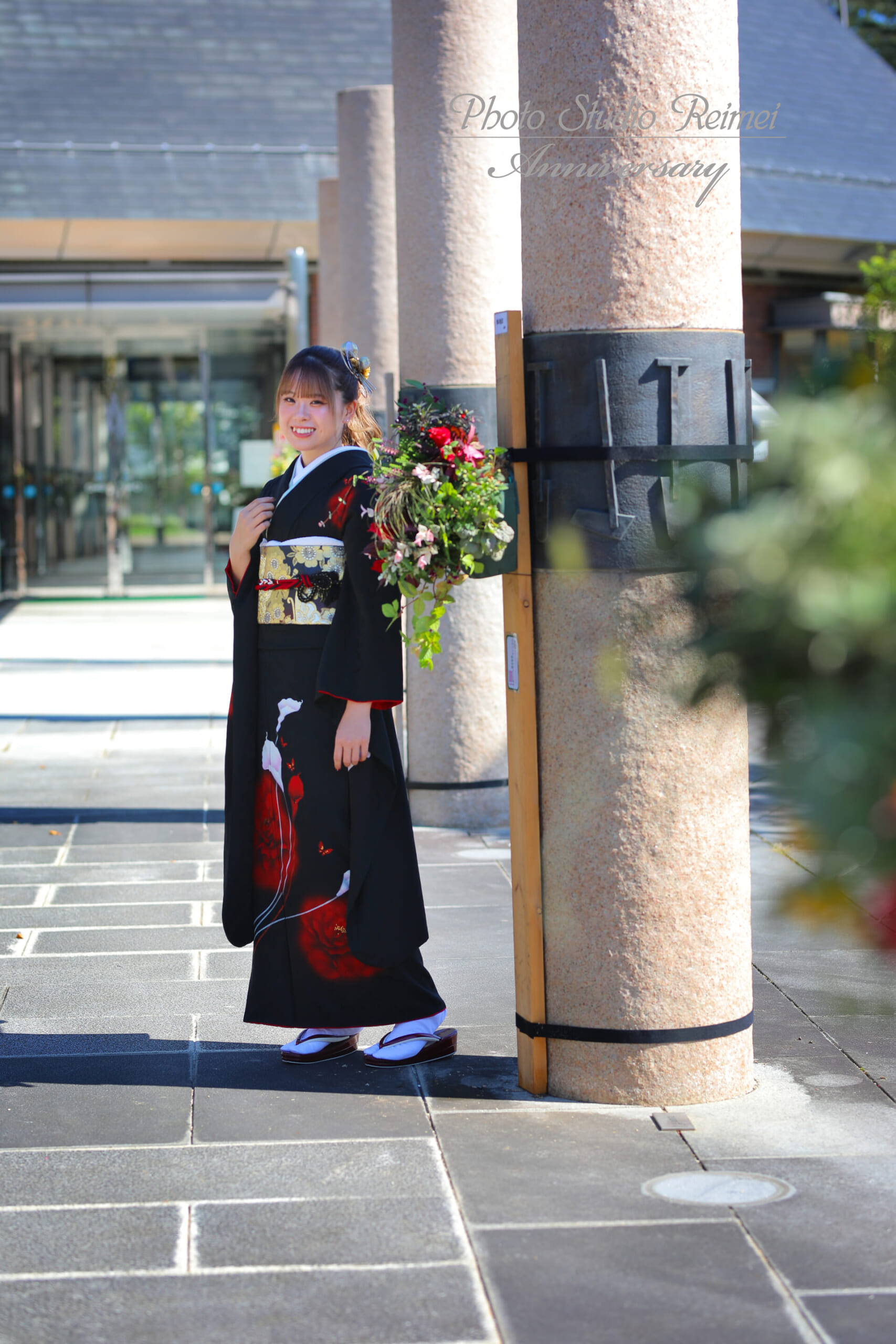 黒い振袖姿で屋外ロケーション撮影をする成人女性