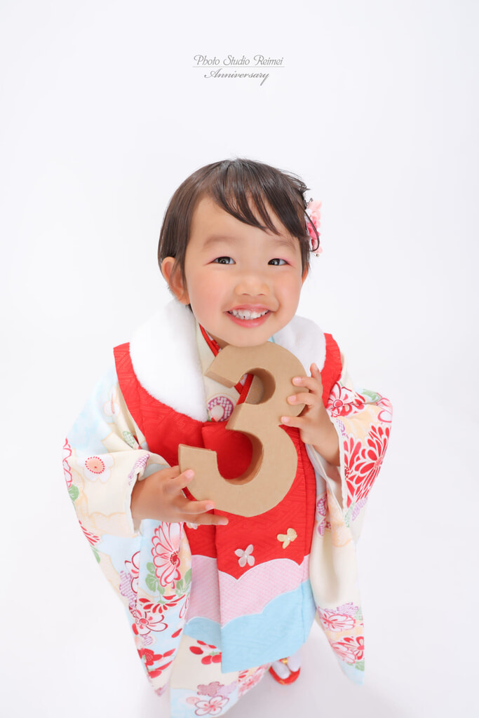 赤い被布姿で笑顔を見せるお子さま